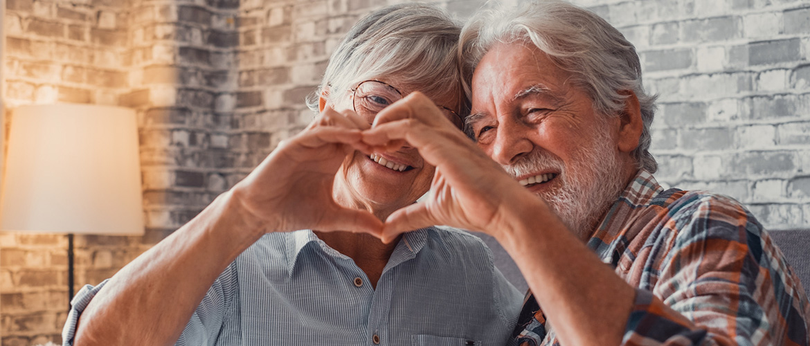 Older couple uses their hands to make a heart sign