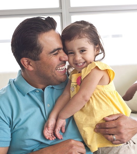 Father hugging his smiling daughter.