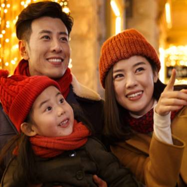 familia feliz sonriendo bajo luces navideñas