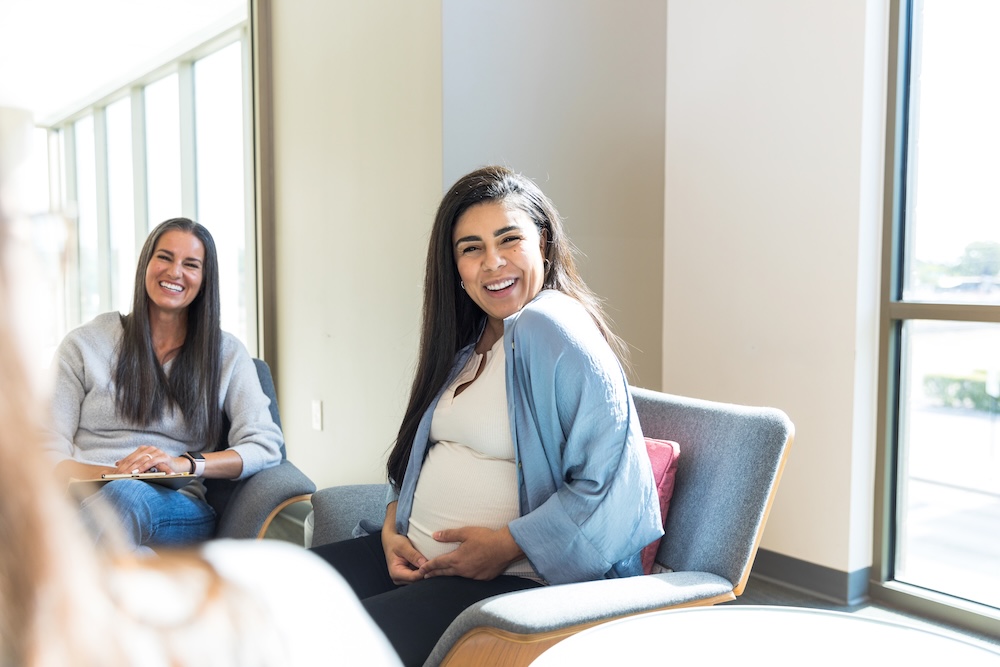 Pregnant woman sitting and smiling in a waiting room
