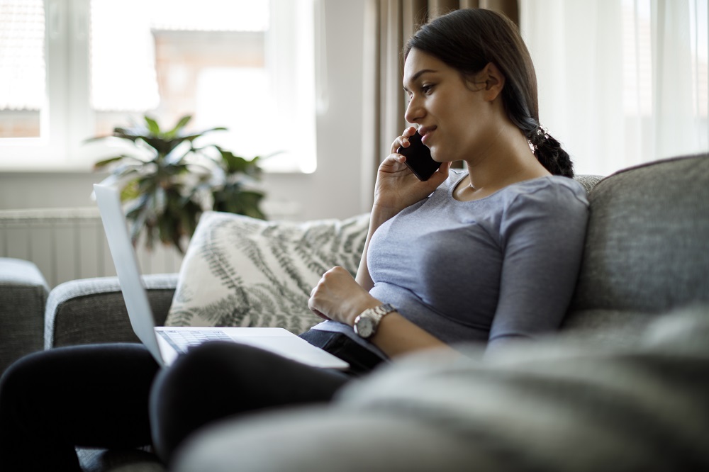 A woman looking at her computer while speaking on the phone.