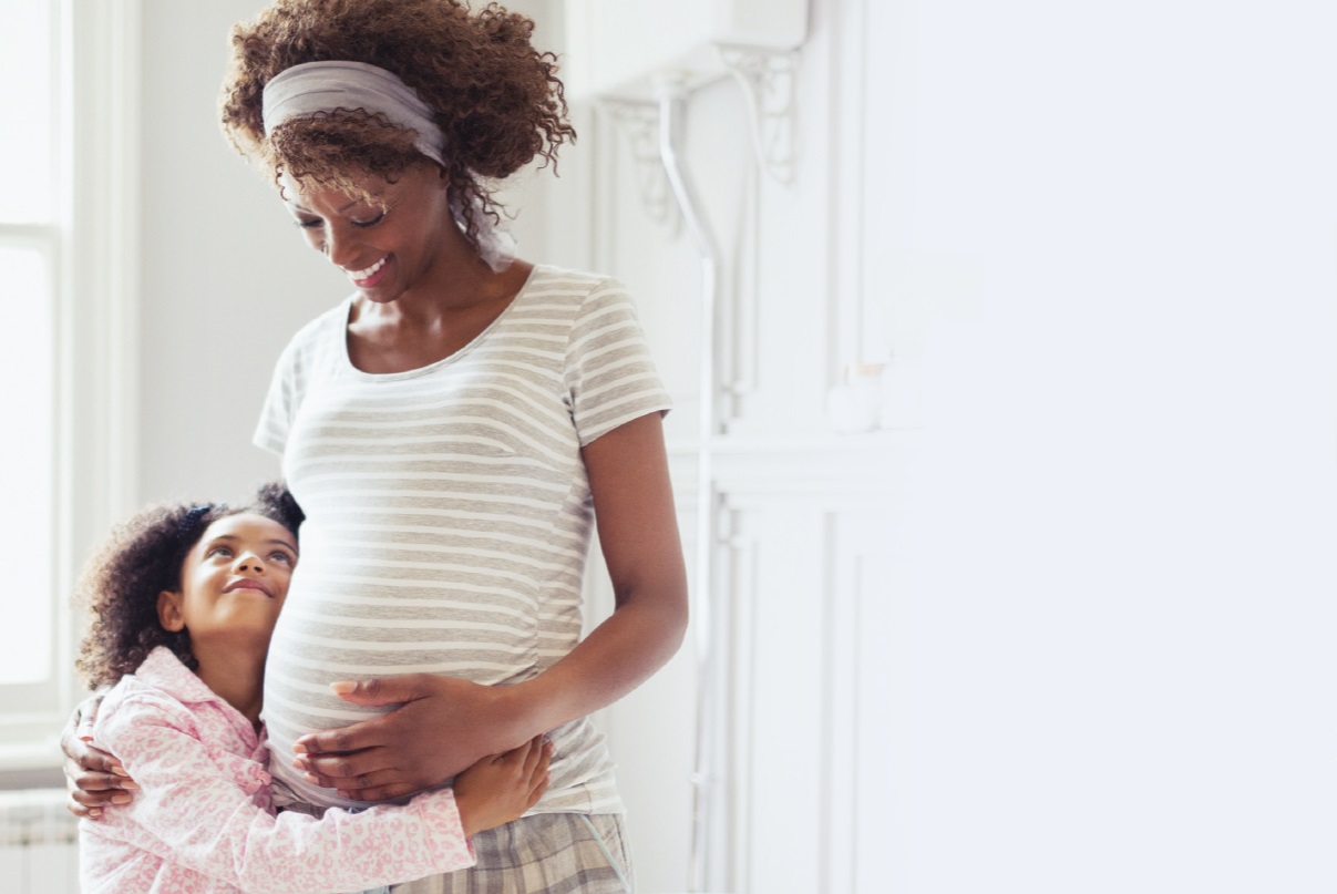 Hija pequeña abrazando a su madre embarazada