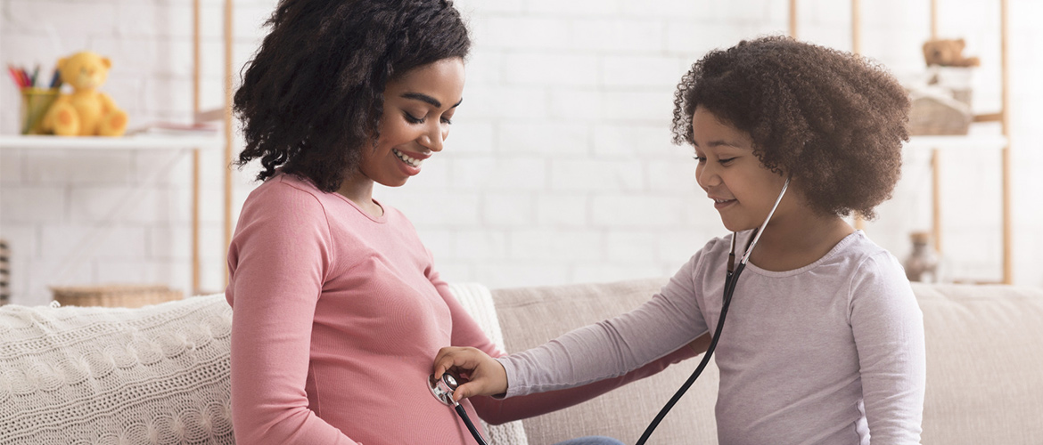 A child puts a stethoscope on a pregnant woman's abdomen