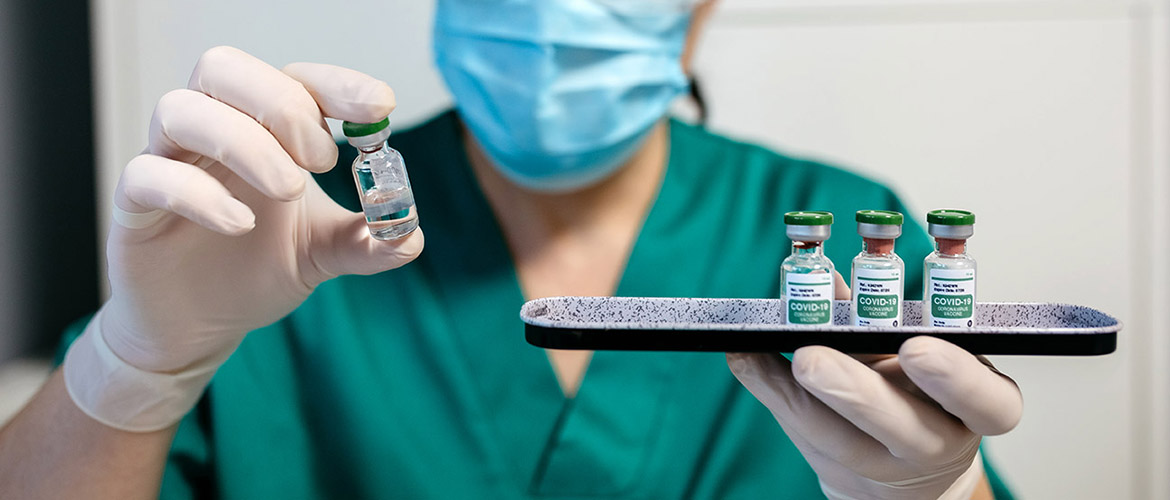 Clinician in mask holds vials of COVID-19 vaccine