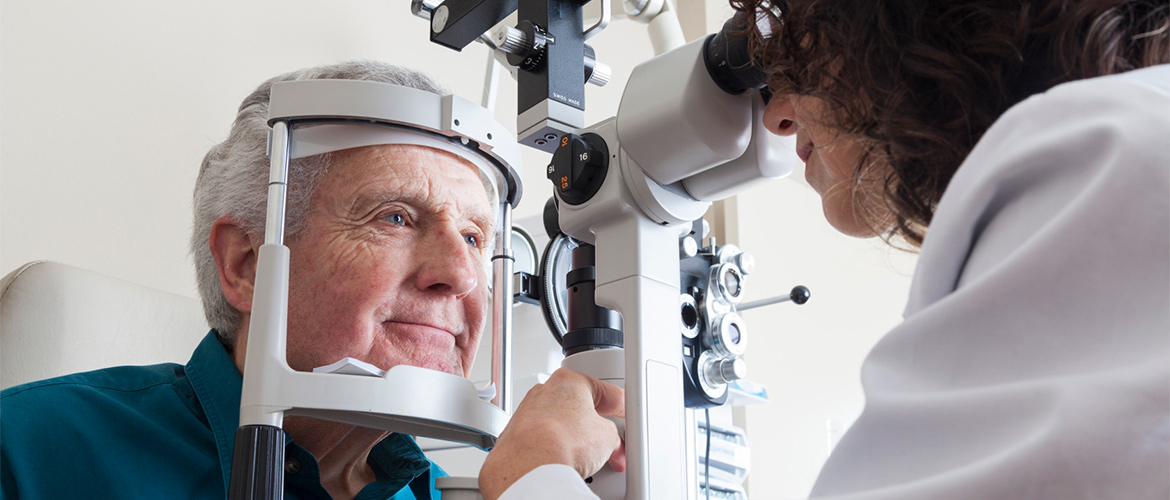 An eye doctor performs a vision check on an older man