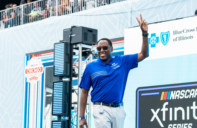 BCBSIL President Stephen Harris walks across a stage and waves.