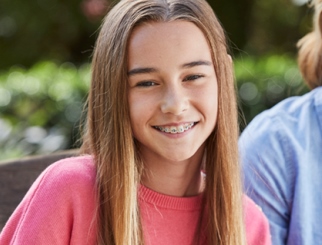 Teenage girl with braces, smiling at the camera. 