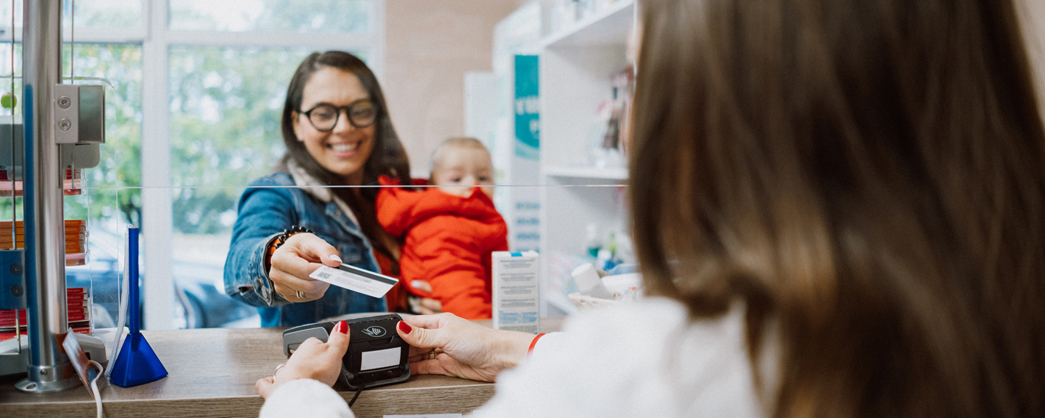 A woman holding a small child at a pharmacy counter