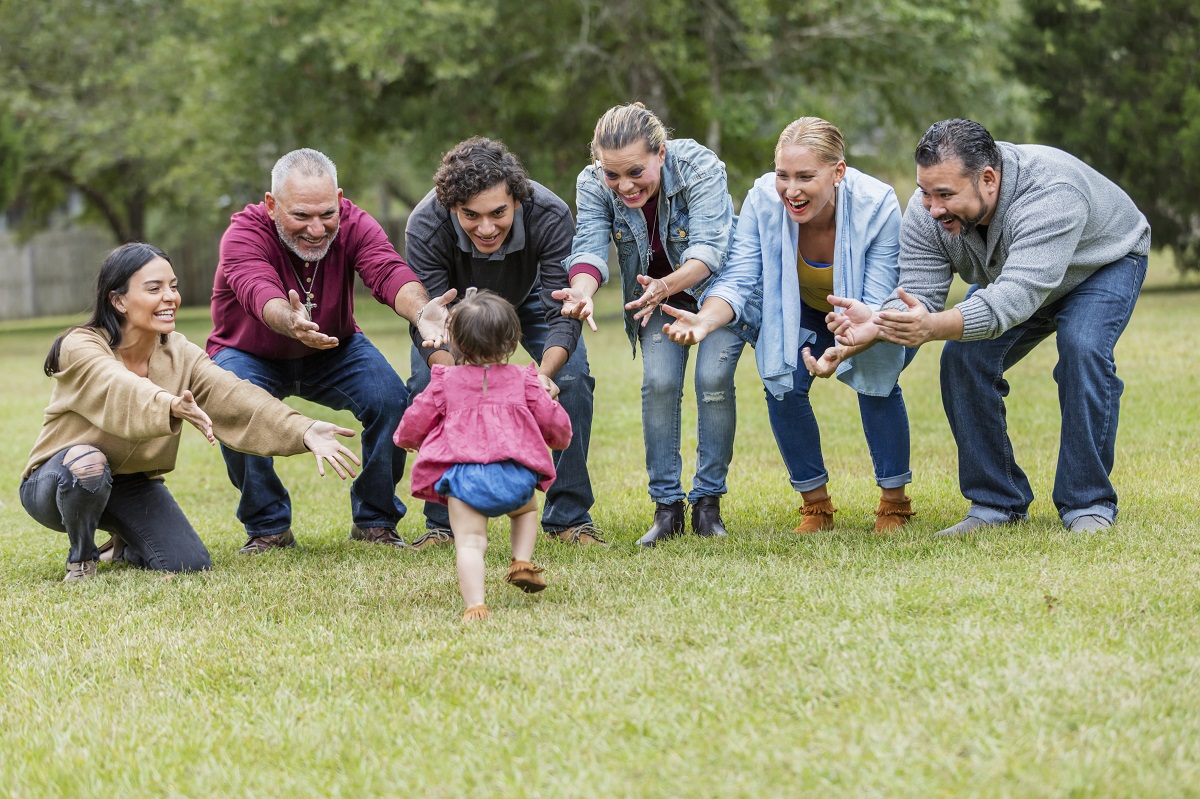 Niña pequeña caminando hacia sus familiares con los brazos extendidos