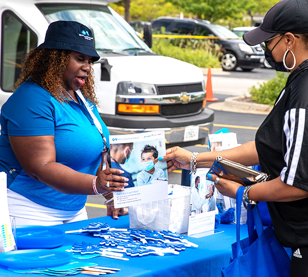 BCBSIL employee handing informational flyer to community member at block party