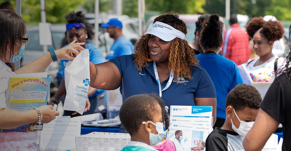 BCBSIL employee handing resources to community member at block party