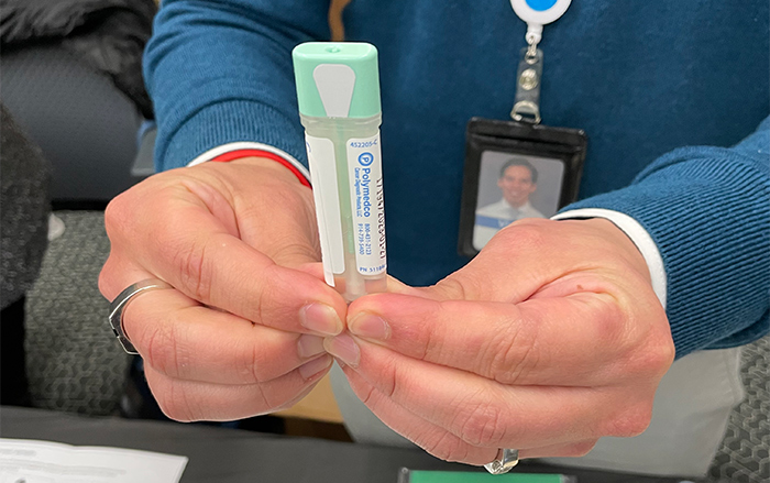A BCBSIL employee holds an at-home test for colorectal cancer screening.