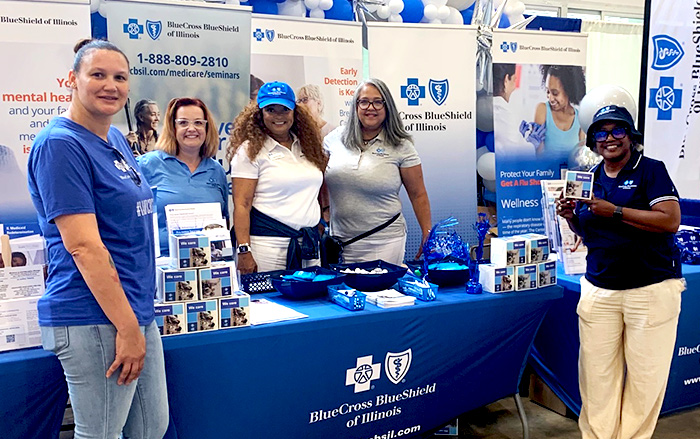 BCBSIL Employees stand near a booth at an insurance enrollment event.