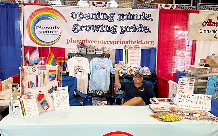 En una mesa en un evento, Phoenix Center Springfield brinda información sobre sus servicios para personas con VIH y miembros de la comunidad LGBTQ.