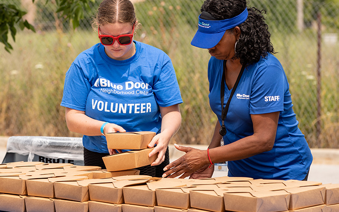 Dos personas voluntarias de BCBSIL apilan cajas de comida.