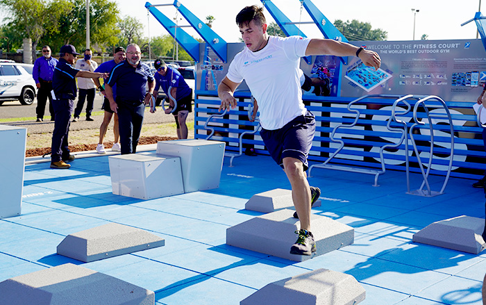 Un joven muestra cómo realizar ejercicios en un nuevo centro de acondicionamiento físico al aire libre.