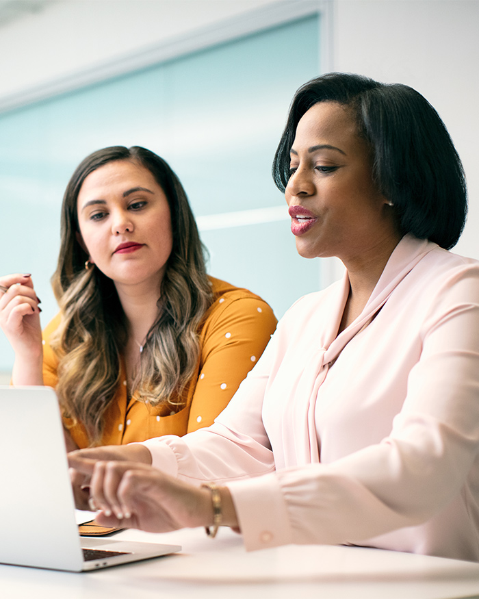 Dos mujeres bien vestidas dialogando sobre negocios en una oficina.