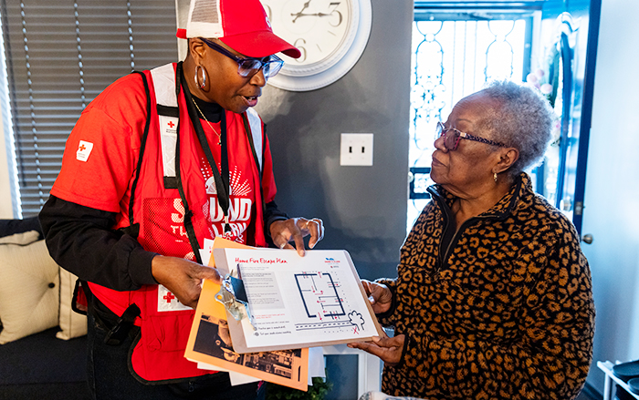 American Red Cross worker with clipboard walks woman through safety routes and tips