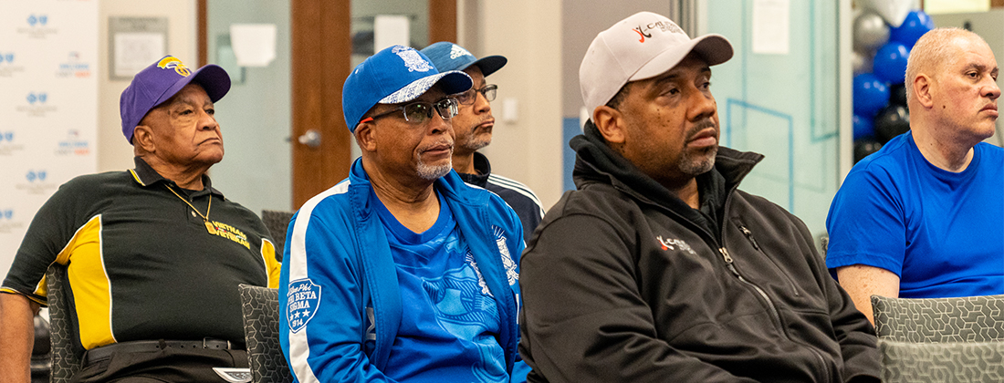 Rows of men sit in audience at a community mens's health event