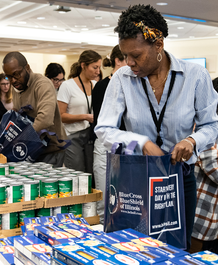 Una mujer llena una bolsa con alimentos en un evento de voluntariado para empleados