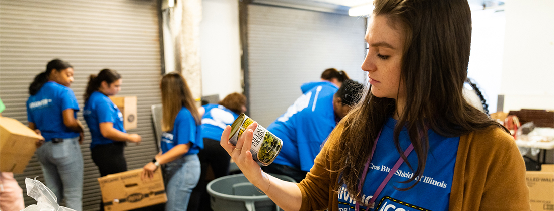 BCBSIL employee holds up canned good at employee volunteer event