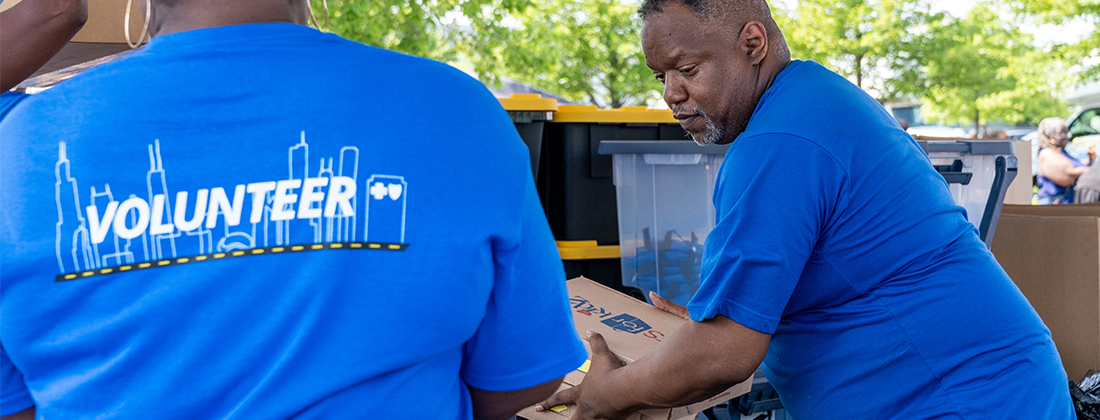 Dos voluntarios moviendo cajas de paquetes de cuidado en el evento