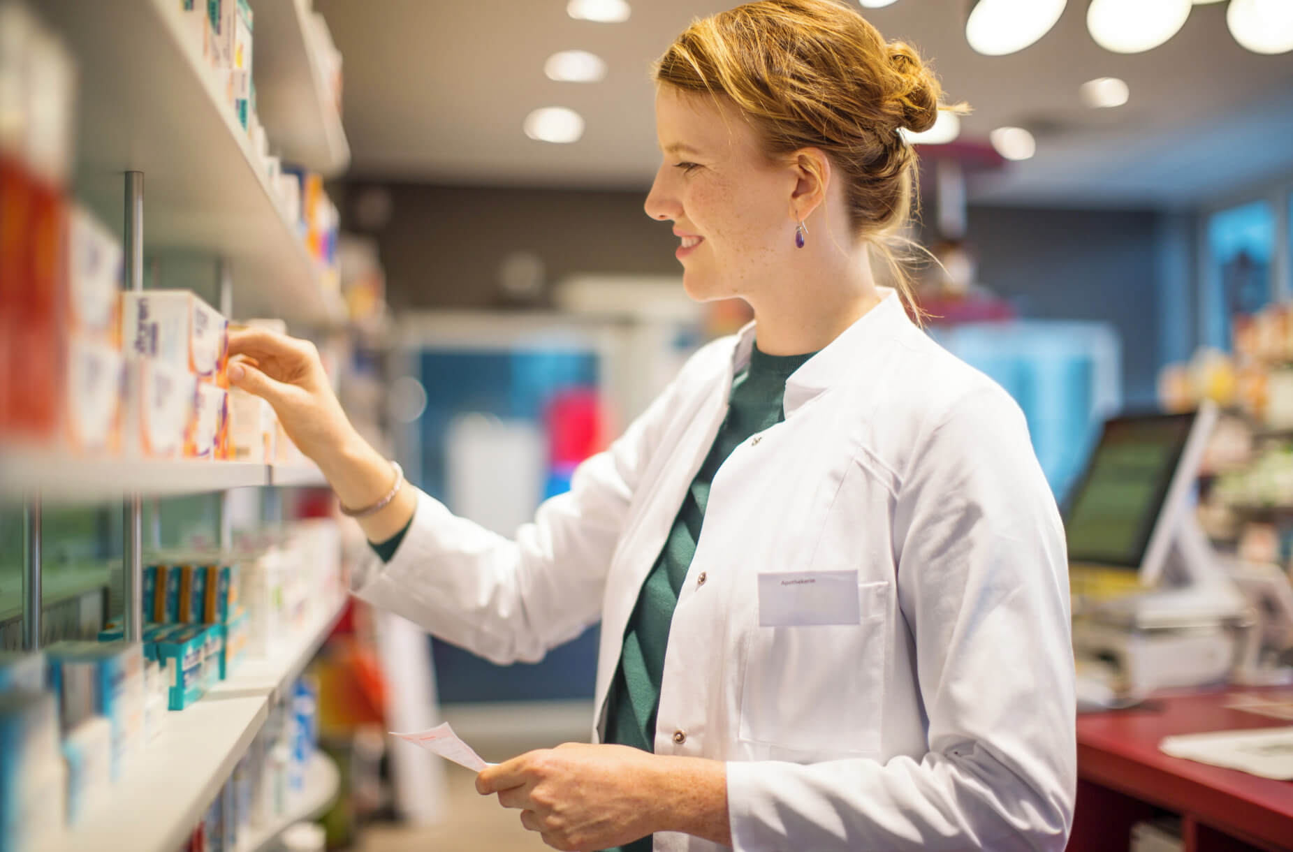 Farmacéutica sonriente entregando un medicamento con receta