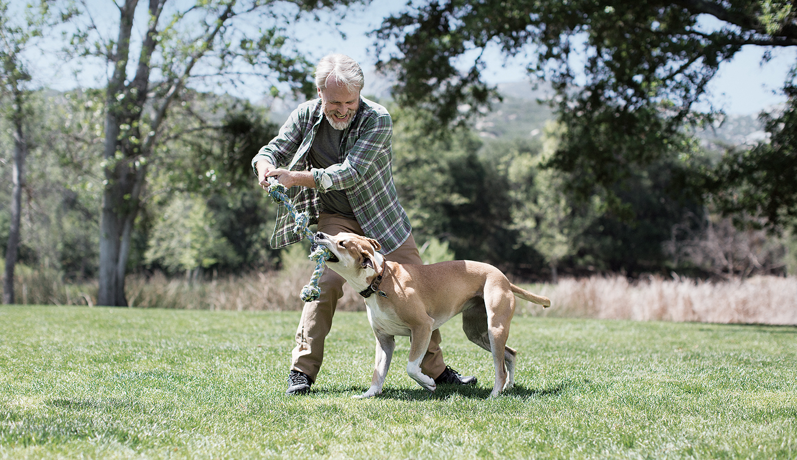 Senior man playing with his dog outside, confident in his Medicare decision.  